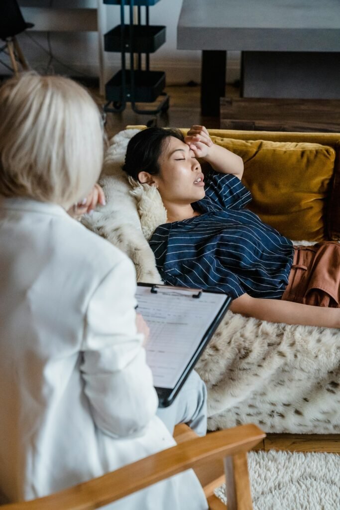 Woman in therapy session with psychologist, expressing emotions, lying on couch.